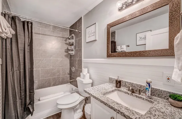 a bathroom with a granite countertop sink toilet and shower