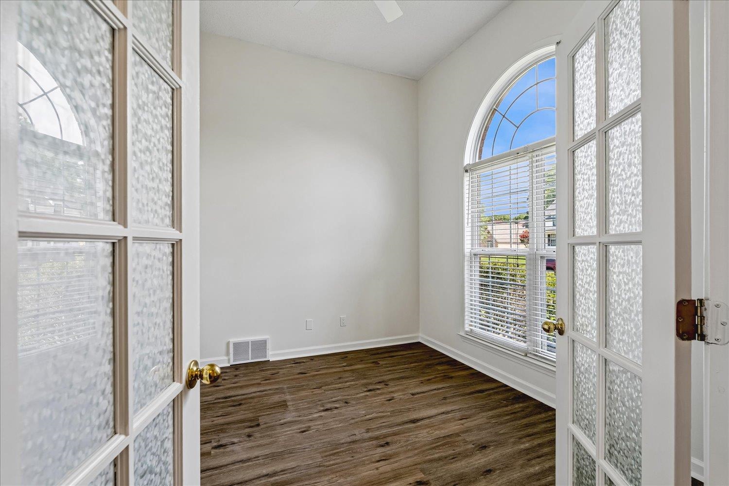 6335 Needle Ridge Road Bartlett, TN 38135 - Photo 4 of 25 French doors with textured glass panels open to a room featuring an arched window, white blinds, and wood-finish flooring