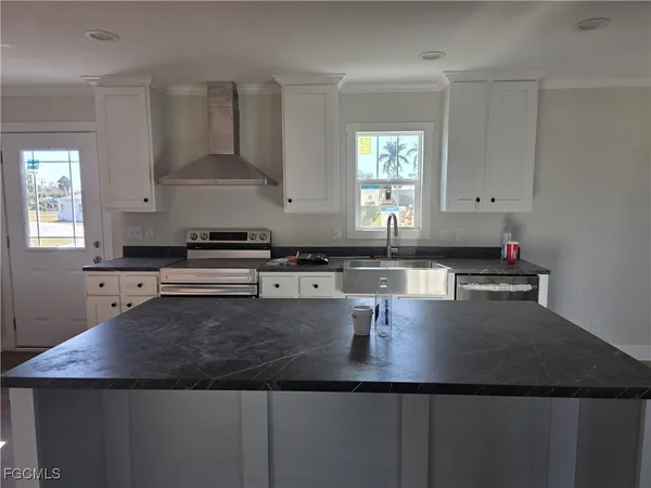 a kitchen with kitchen island granite countertop a sink a stove and cabinets