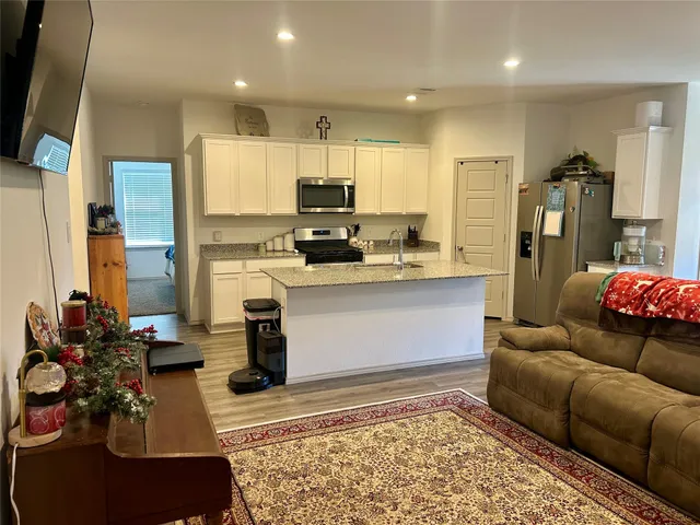 a living room with stainless steel appliances furniture stove and kitchen view