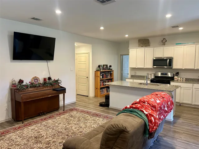 a living room with stainless steel appliances furniture and a flat screen tv