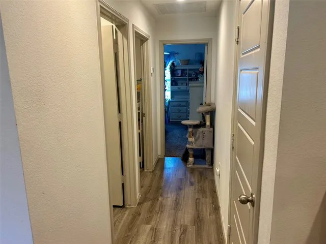 a view of a hallway with wooden floor and closet