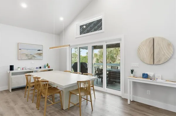 a kitchen with stainless steel appliances granite countertop a refrigerator a sink dishwasher a stove and a dining table with wooden floor