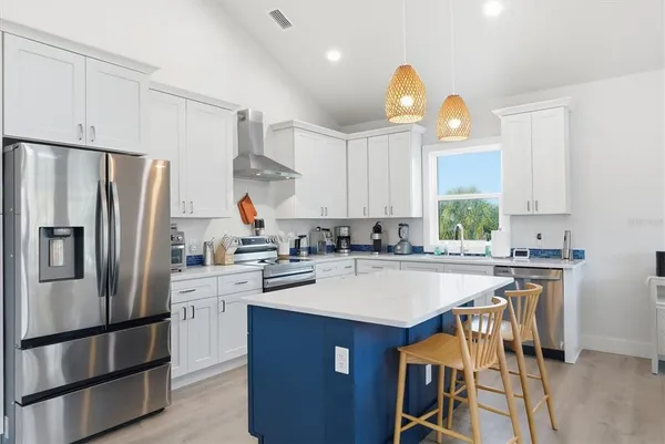 a kitchen with a stove a refrigerator and a dining table with wooden floor