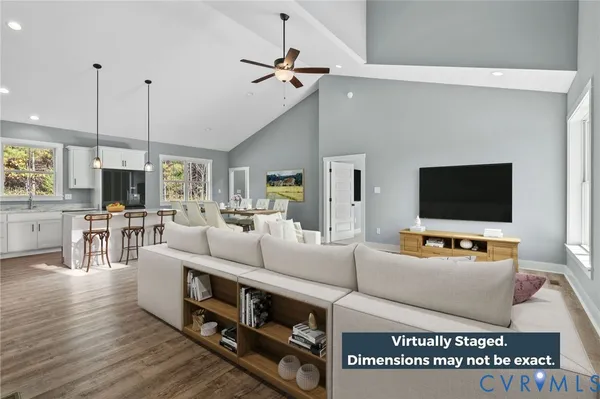 a living room with a bed a flat screen tv and a ceiling fan