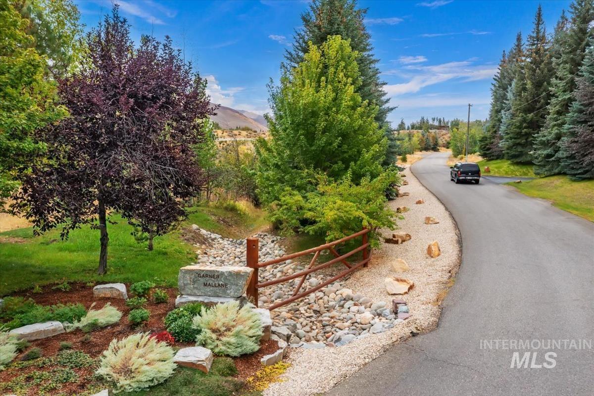 106 Hidden Hollow Road Hailey, ID 83333 - Photo 49 of 49 Manicured landscaping, natural stone accents, decorative wood fencing, paved driveway, and mature trees