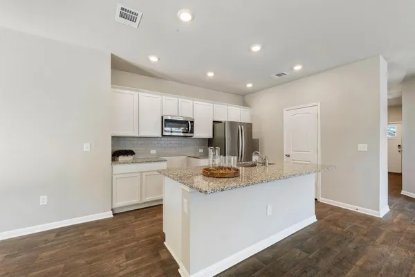 a kitchen with stainless steel appliances granite countertop a sink a stove a refrigerator and white cabinets