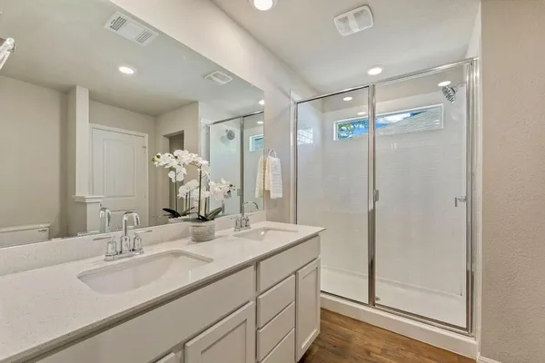 a bathroom with a double vanity sink mirror and shower