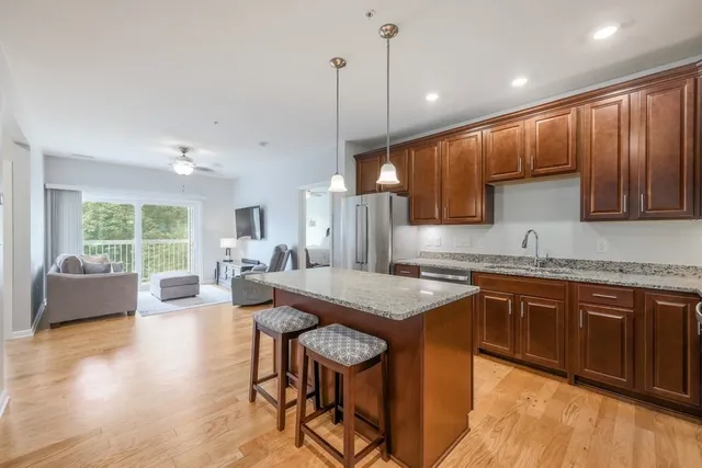 a kitchen with stainless steel appliances granite countertop wooden cabinets a sink a stove a dining table and chairs
