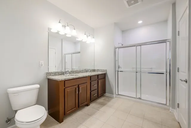 a bathroom with a granite countertop toilet a sink and a mirror