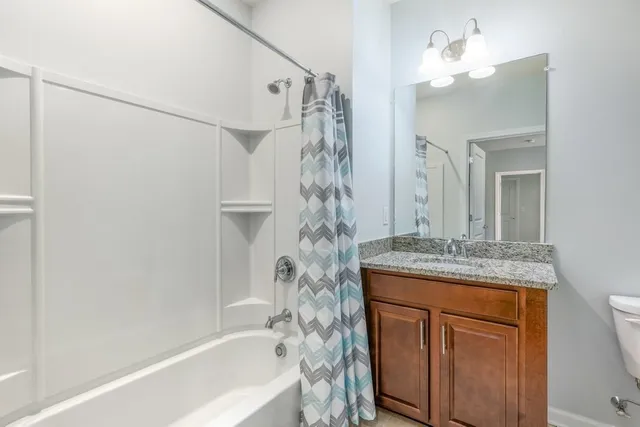 a bathroom with a granite countertop sink a mirror a vanity and a bathtub