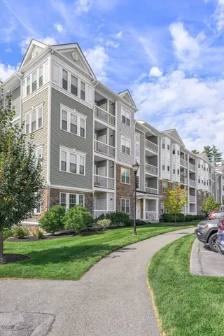 a front view of a building with garden and trees