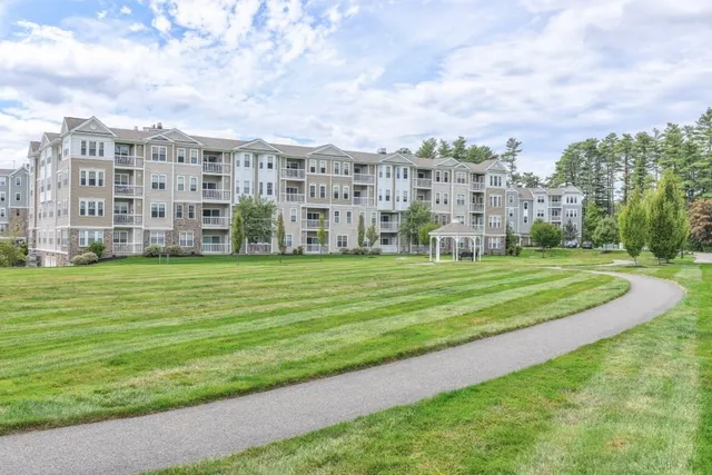 a view of a building with a big yard and trees