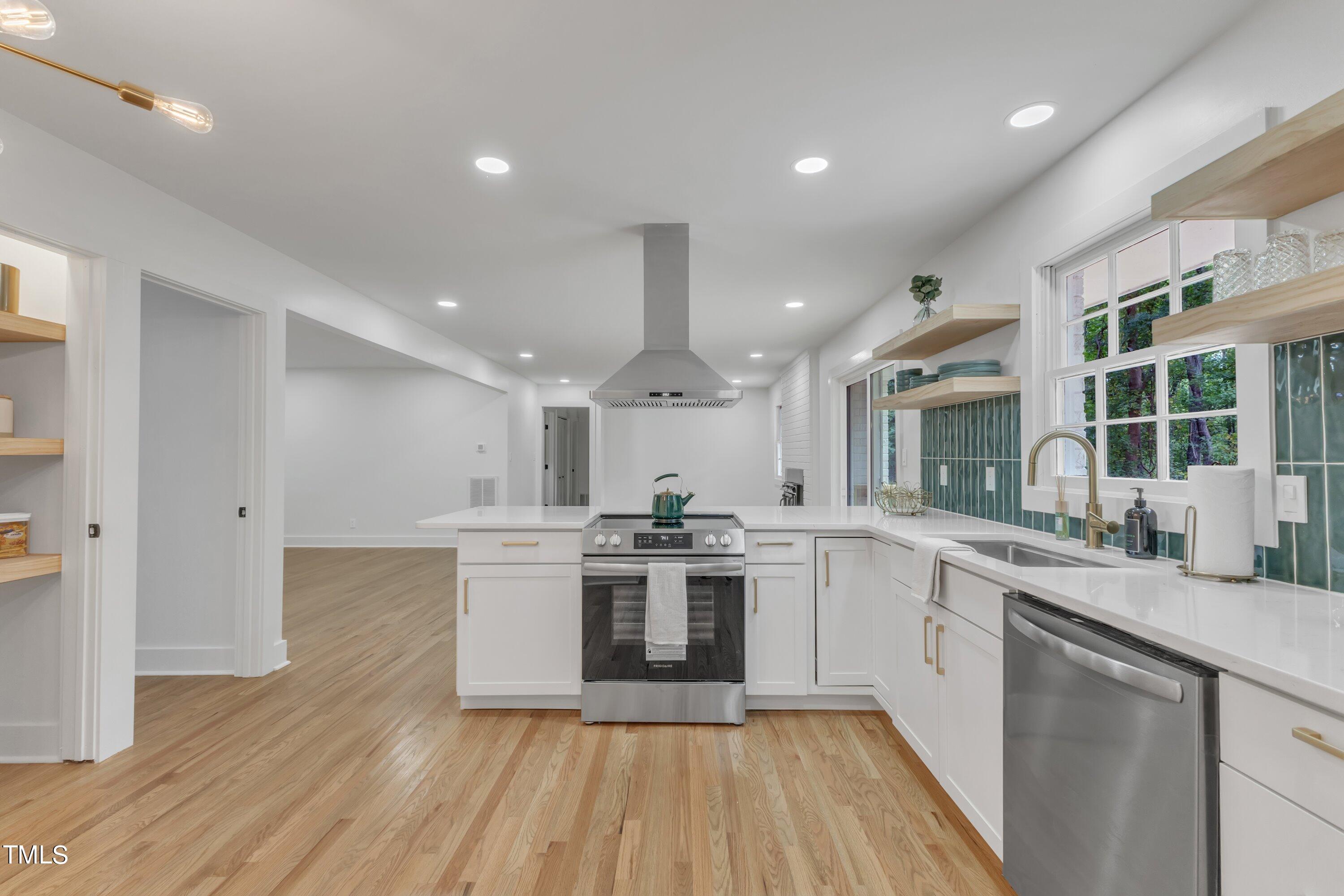 3023 Creech Road Garner, NC 27529 - Photo 14 of 42 a kitchen with stainless steel appliances granite countertop hardwood floor sink stove and wooden cabinets