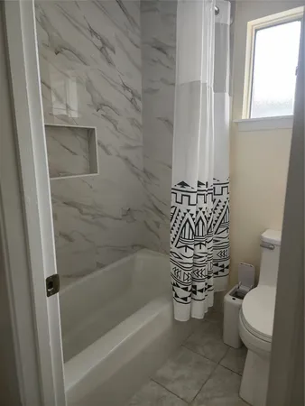 an empty room with wooden floor chandelier fan and windows