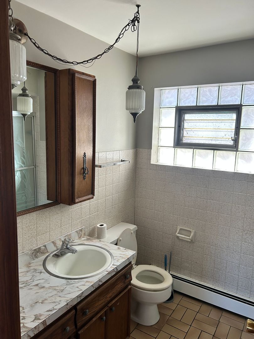 5645 West 63rd Place, Unit 2 Chicago, IL 60638 - Photo 12 of 13 a bathroom with a granite countertop toilet a sink and a mirror