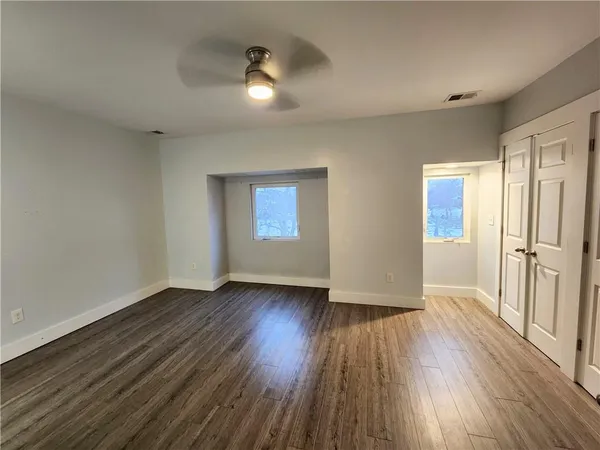 an empty room with wooden floor and windows