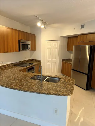 a kitchen with stainless steel appliances granite countertop a sink and a refrigerator