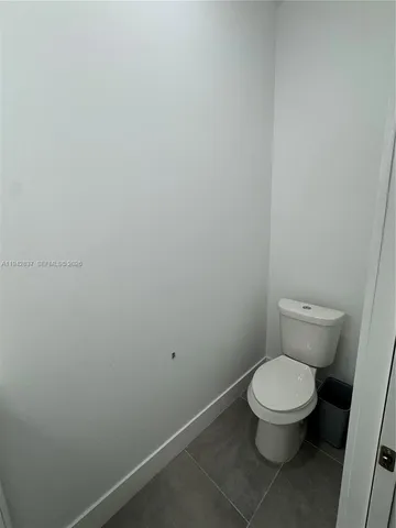 a white toilet sitting next to a white wall