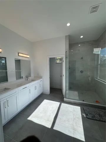 a large bathroom with a double vanity sink a large mirror and shower