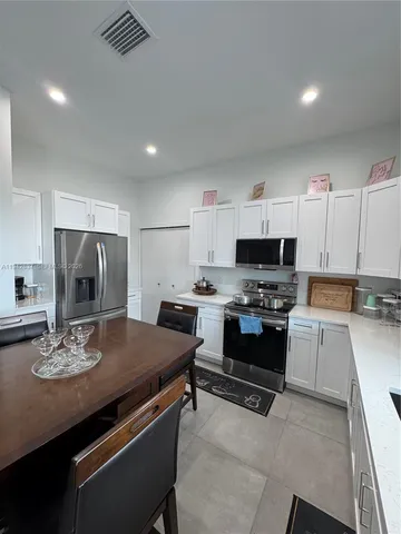 a kitchen with stainless steel appliances a stove a sink a microwave a refrigerator and cabinets