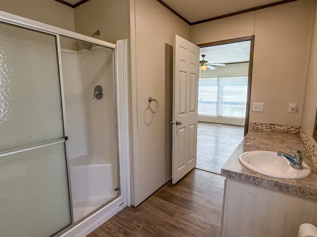 a bathroom with a granite countertop sink a mirror and shower