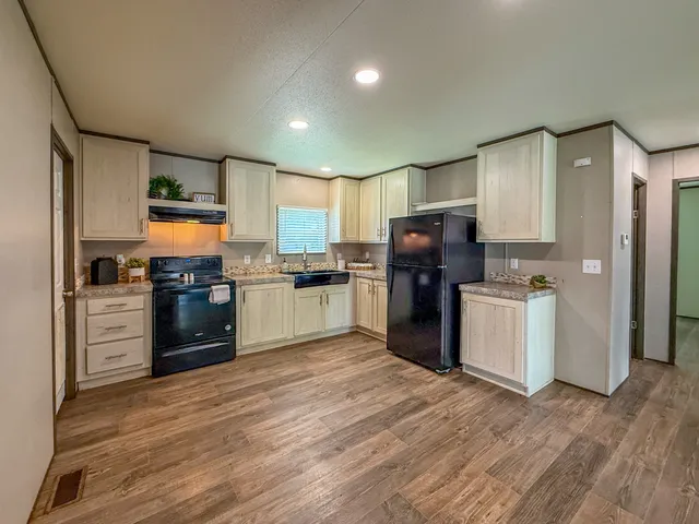 a kitchen with granite countertop a refrigerator and steel appliances