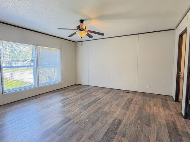 a view of an empty room with a window and wooden floor