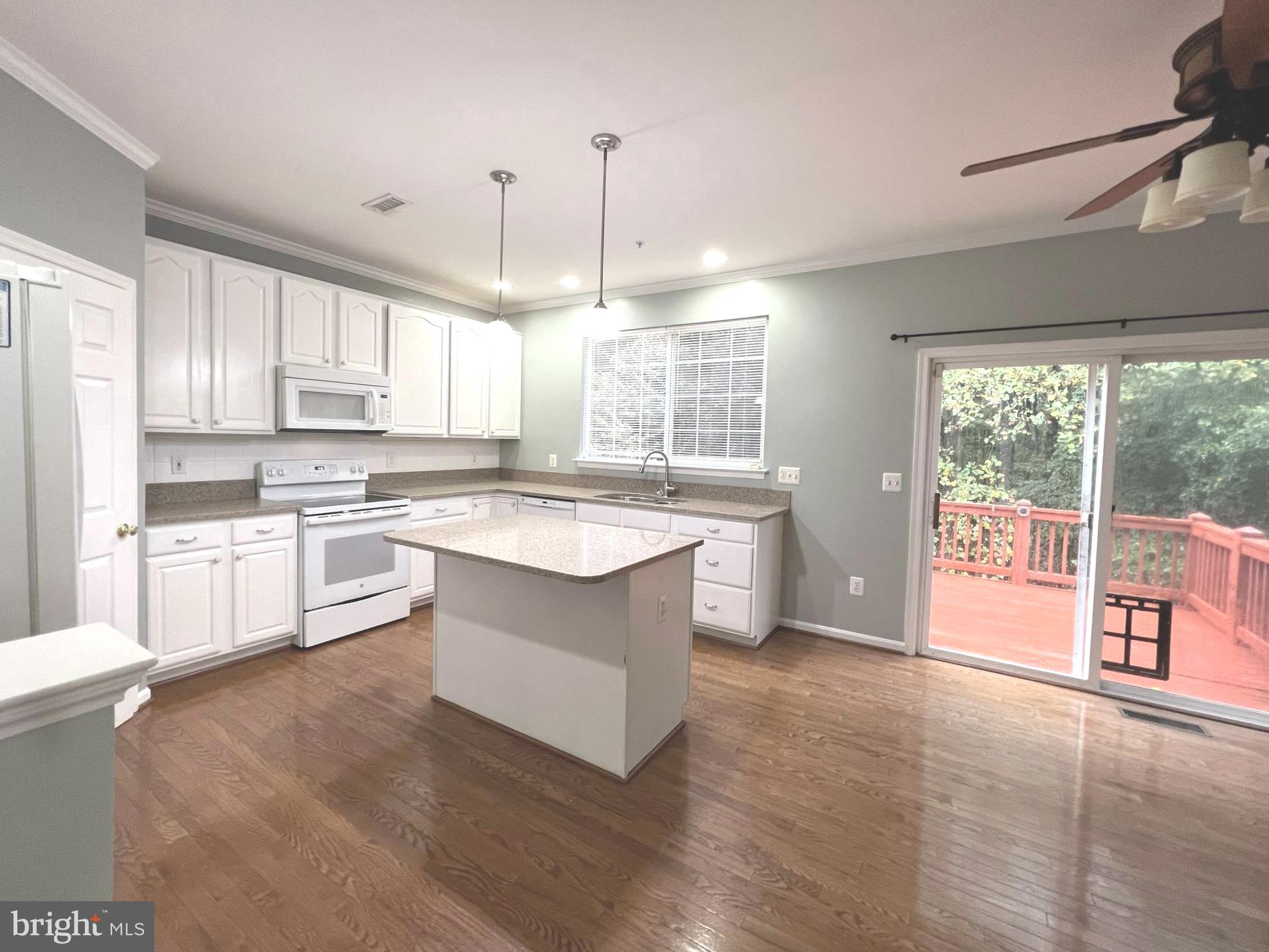 2610 Streamview Drive Odenton, MD 21113 - Photo 4 of 23 a large kitchen with kitchen island granite countertop a stove a sink a refrigerator and white cabinets with wooden floor