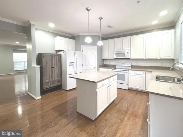 a kitchen with stainless steel appliances granite countertop a sink a stove a refrigerator and island with wooden floor