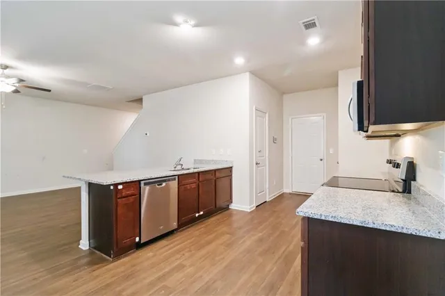 a kitchen with stainless steel appliances granite countertop a sink a stove and a wooden floors
