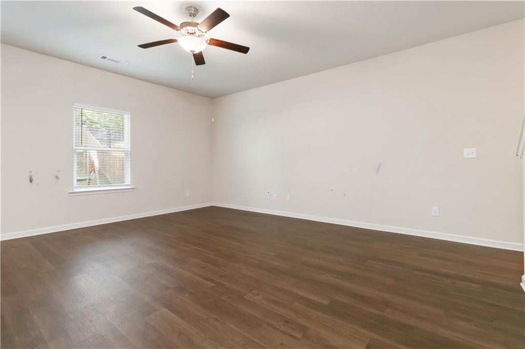 10794 Wheeler Trace Hampton, GA 30228 - Photo 10 of 35 an empty room with wooden floor ceiling fan and windows