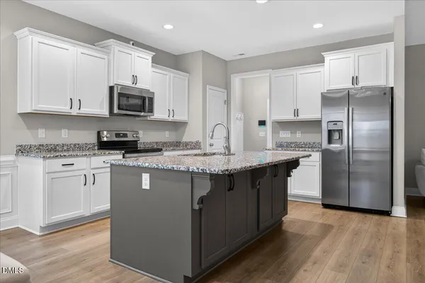 a kitchen with kitchen island granite countertop a sink cabinets and wooden floor