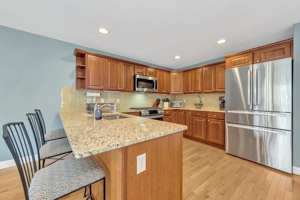 24 River Point Drive, Unit 6 Ipswich, MA 01938 - Photo 12 of 27 a kitchen with stainless steel appliances granite countertop a refrigerator sink and wooden cabinets