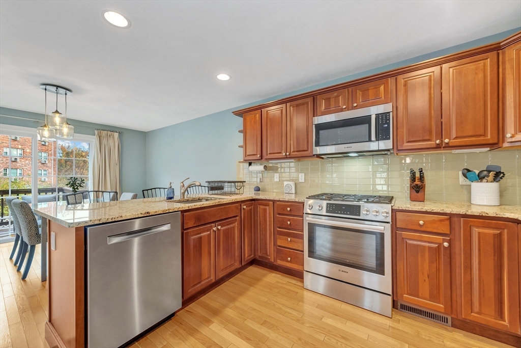 24 River Point Drive, Unit 6 Ipswich, MA 01938 - Photo 10 of 27 a kitchen with stainless steel appliances granite countertop a stove top oven a sink and dishwasher a oven with wooden cabinets