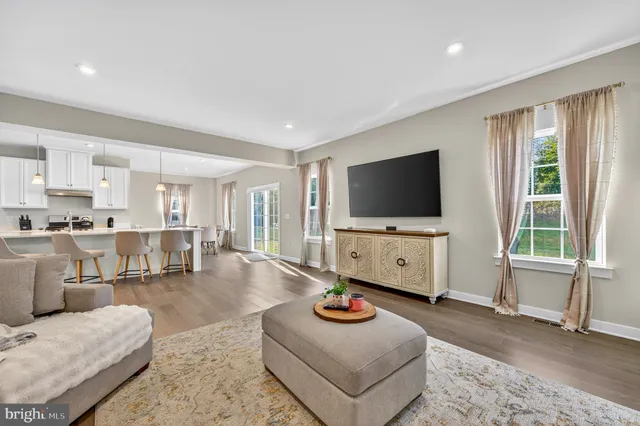 a kitchen with stainless steel appliances granite countertop a stove a refrigerator a kitchen island a dining table and chairs with wooden floor