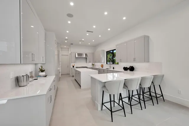 a large white kitchen with stainless steel appliances lots of counter top space and cabinets