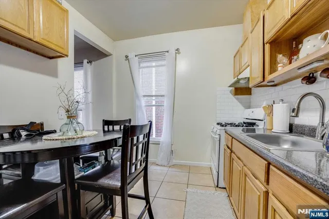 a kitchen with stainless steel appliances kitchen island granite countertop a table chairs in it and a wooden floor