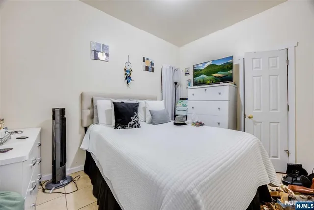 a bedroom with a bed and a flat tv screen on the dresser