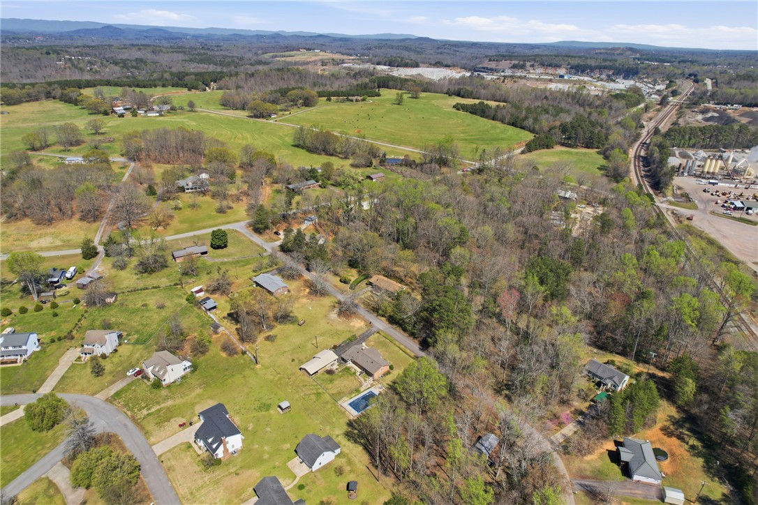 0 Springdale Avenue Liberty, SC 29657 - Photo 10 of 12 An aerial view showcases houses nestled amidst expansive green fields and distant mountains.