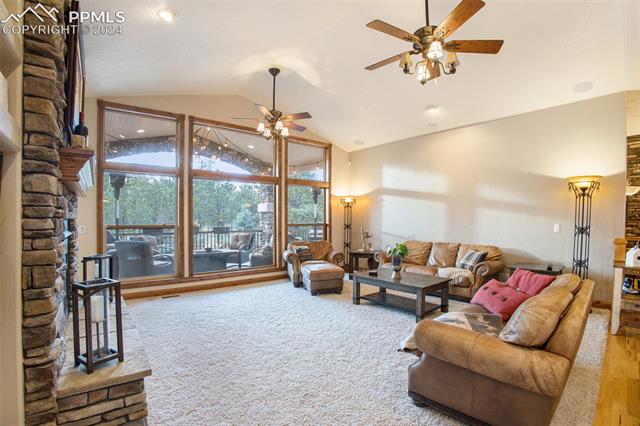 Carpeted living room featuring high vaulted ceiling and ceiling fan