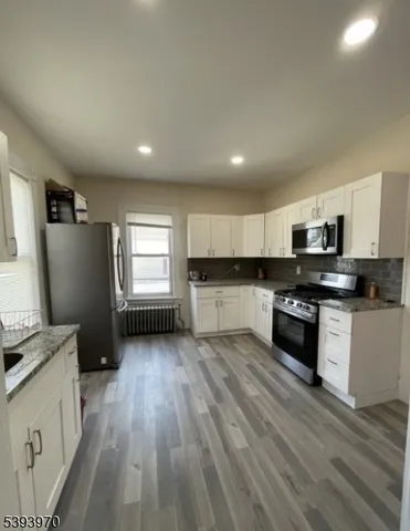 a kitchen with stainless steel appliances granite countertop a refrigerator a stove top oven a sink and dishwasher with wooden floor