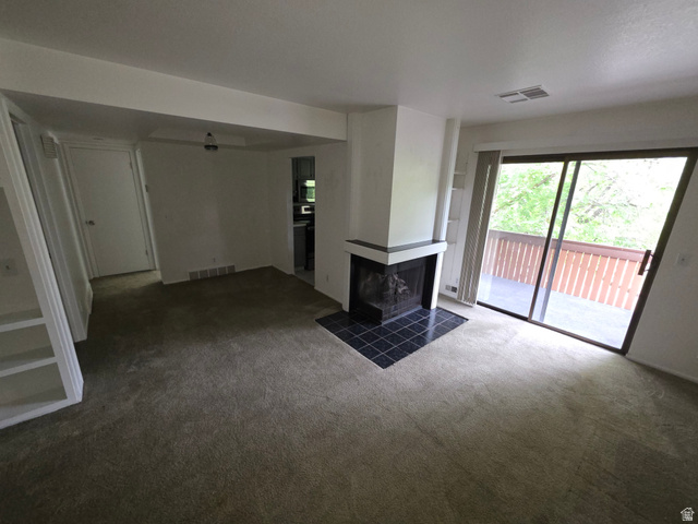 6852 Countrywoods Circle, Unit 5D Midvale, UT 84047 - Photo 14 of 50 Carpeted living space featuring a fireplace with a black tile hearth and a sliding glass door leading to an outdoor balcony