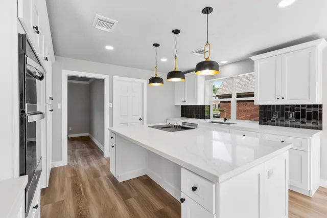 a kitchen with a sink a counter top space stainless steel appliances and a chandelier
