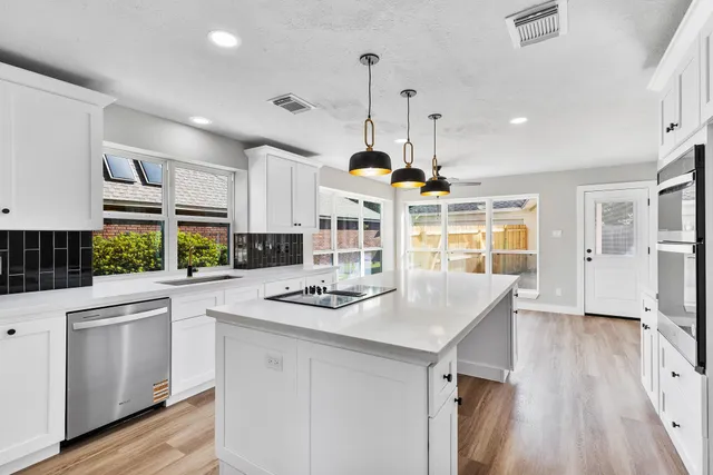 a kitchen with stainless steel appliances granite countertop a stove a sink dishwasher and a refrigerator with wooden floor