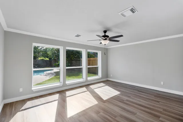 a view of an empty room with a window and wooden floor
