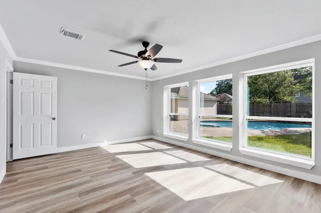 a view of an empty room with a window and wooden floor