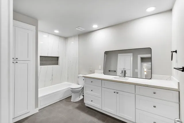a bathroom with a double vanity sink a large mirror and a bathtub