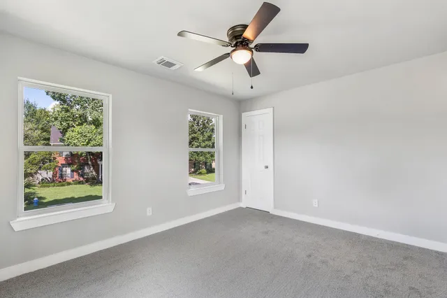 an empty room with window and ceiling fan