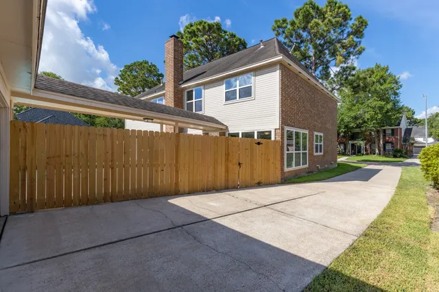 a view of backyard with large tree and wooden fence